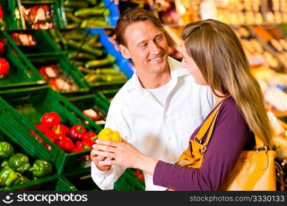Couple in a supermarket at the vegetable shelf shopping for groceries, they are checking out the groceries
