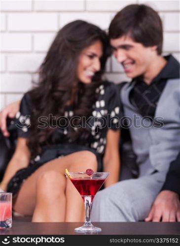 Couple in background on date in bar or night club with wine glass in focus.