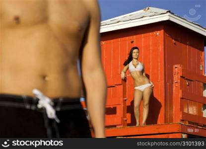 Couple in bathing suits standing on beach near lifeguard station