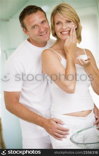 Couple in bathroom with face cream smiling