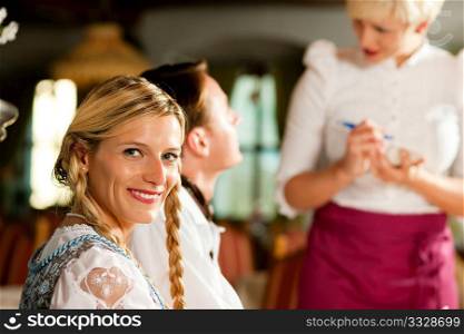 Couple in Bavarian Restaurant ordering food and drinks from the waitress