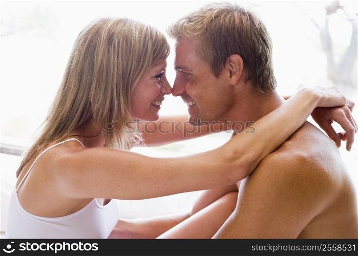 Couple in bedroom embracing and smiling