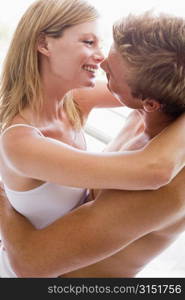 Couple in bedroom embracing and smiling