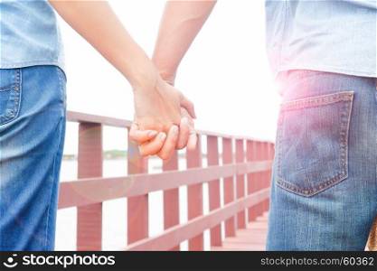 Couple in casual jeans holding hands in summer sunshine