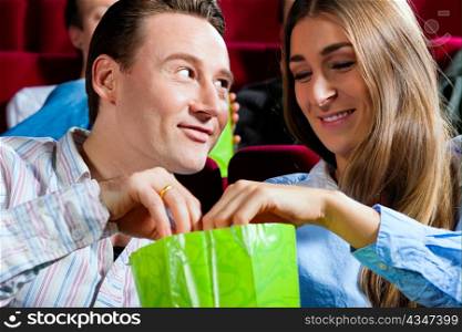 Couple in cinema watching a movie; they eating popcorn
