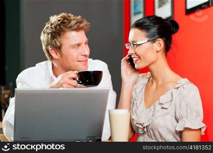 Couple in coffeeshop with laptop and mobile; obviously they are flirting
