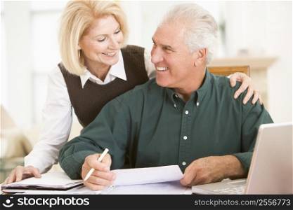Couple in dining room with laptop and paperwork smiling