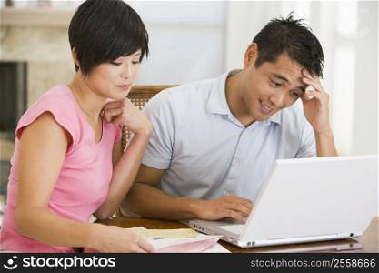 Couple in dining room with laptop looking unhappy