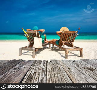 Couple in green relax on a tropical beach at Maldives