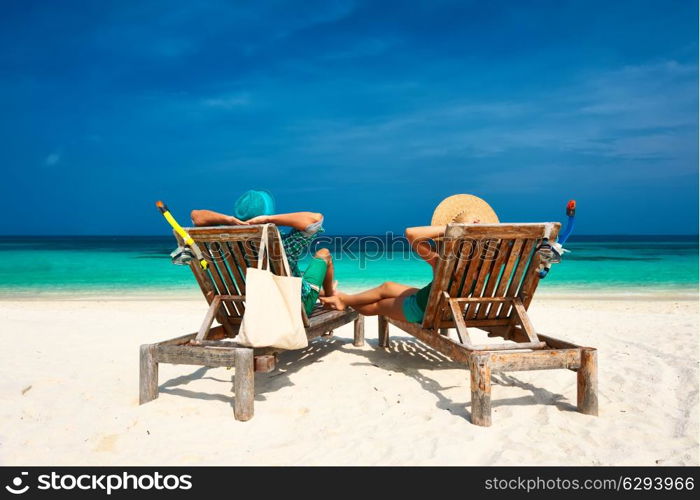 Couple in green relax on a tropical beach at Maldives