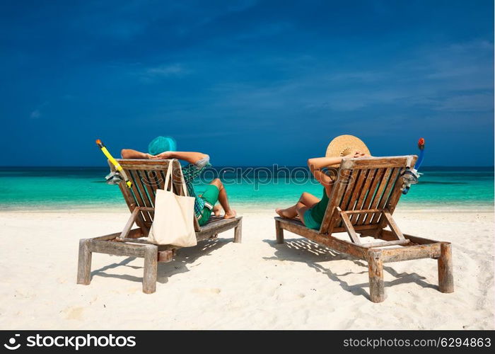 Couple in green relax on a tropical beach at Maldives