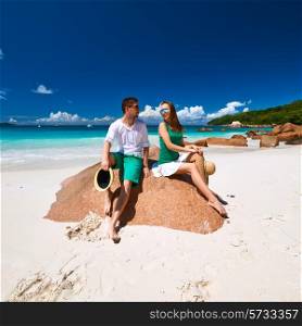 Couple in green sitting on a rock at tropical Seychelles beach
