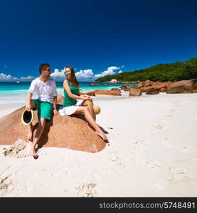 Couple in green sitting on a rock at tropical Seychelles beach