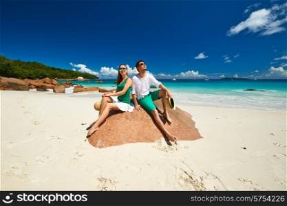 Couple in green sitting on a rock at tropical Seychelles beach