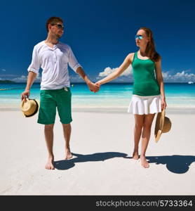 Couple in green walking on a tropical beach at Seychelles