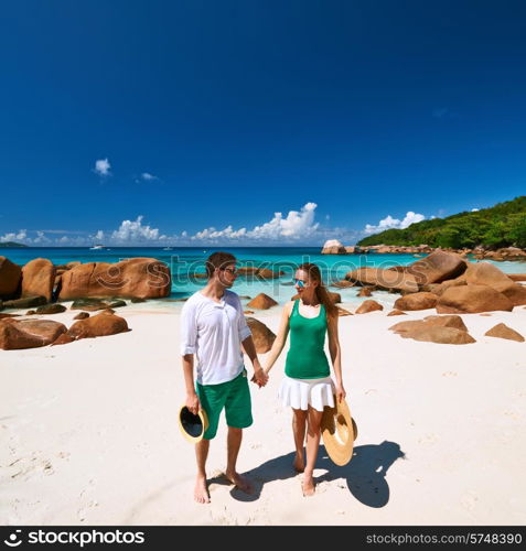 Couple in green walking on a tropical beach at Seychelles