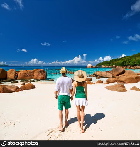 Couple in green walking on a tropical beach at Seychelles