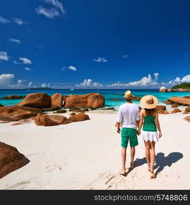 Couple in green walking on a tropical beach at Seychelles