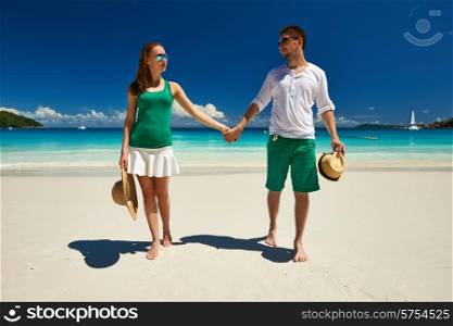 Couple in green walking on a tropical beach at Seychelles