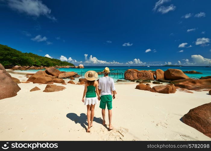 Couple in green walking on a tropical beach at Seychelles