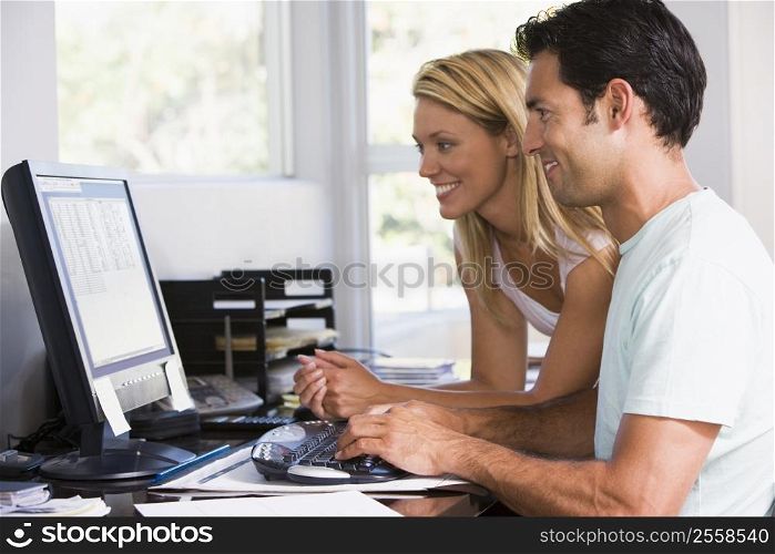 Couple in home office using computer and smiling