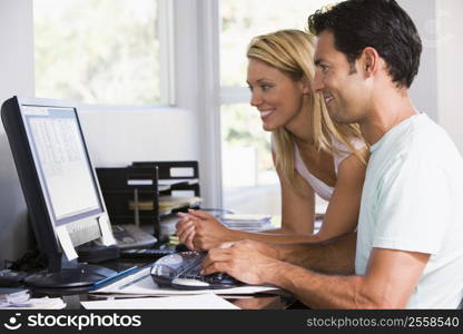 Couple in home office using computer and smiling