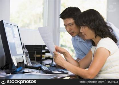 Couple in home office with computer and paperwork pointing