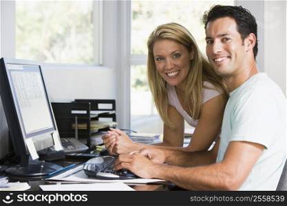 Couple in home office with computer smiling