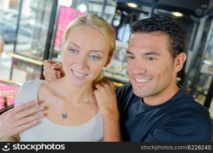 Couple in jewelers, trying on necklace