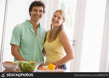 Couple in kitchen cutting up vegetables and smiling