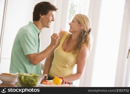 Couple in kitchen cutting up vegetables and smiling