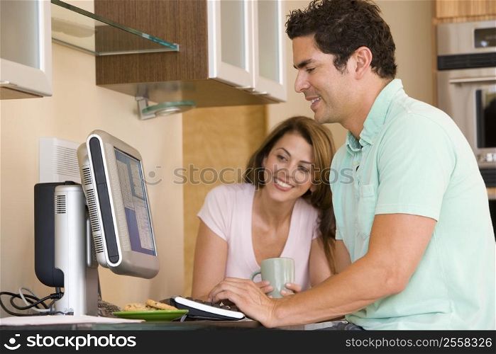 Couple in kitchen with computer and coffee smiling