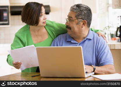 Couple in kitchen with laptop and paperwork