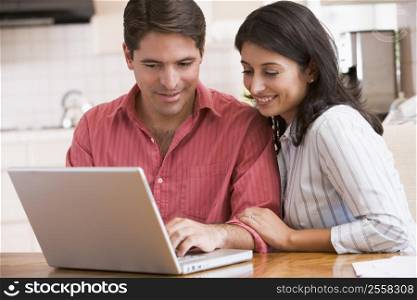 Couple in kitchen with laptop smiling