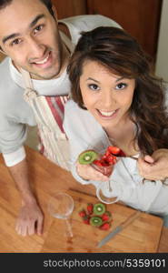 Couple in kitchen with strawberries and kiwi