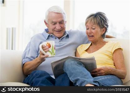 Couple in living room reading newspaper with coffee smiling