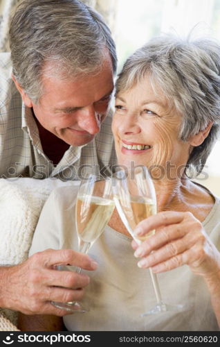 Couple in living room toasting champagne and smiling