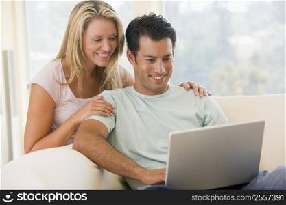 Couple in living room using laptop smiling