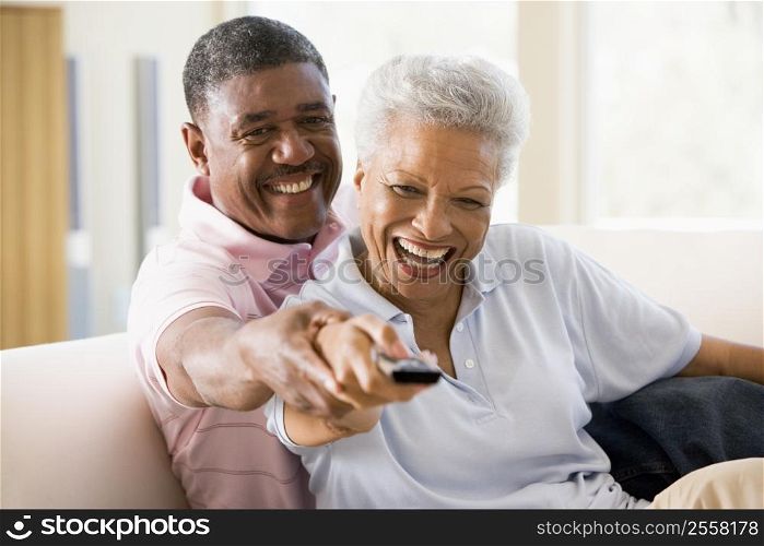 Couple in living room using remote control smiling