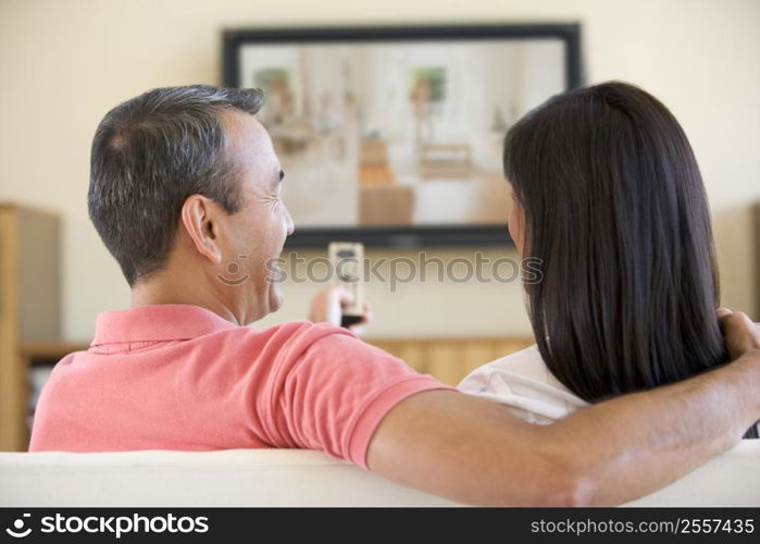 Couple in living room watching television laughing