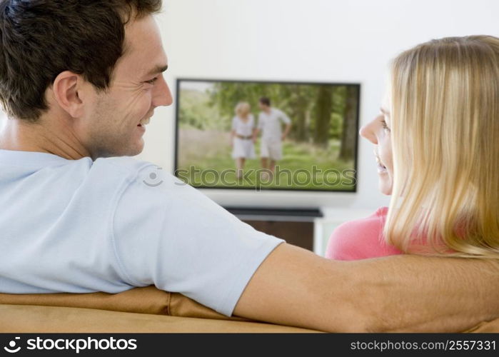 Couple in living room watching television smiling