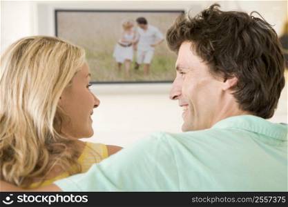 Couple in living room watching television smiling
