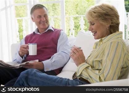 Couple in living room with coffee and newspaper smiling