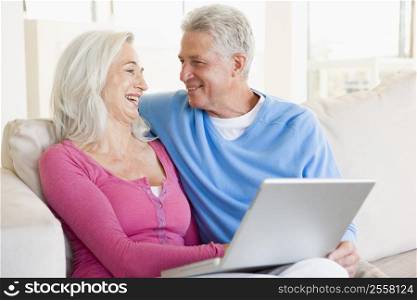 Couple in living room with laptop smiling