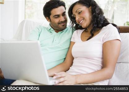 Couple in living room with laptop smiling (high key/selective focus)