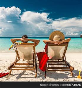 Couple in loungers on a tropical beach at Maldives. Couple in loungers on beach at Maldives
