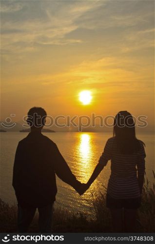 couple in love back light silhouette at lake, sunset background