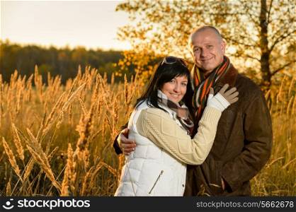 Couple in love embracing in autumn countryside backlit by sunset