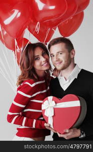 Couple in love. Happy embracing couple in love holding Valentines day gifts and bunch of heart shaped balloons