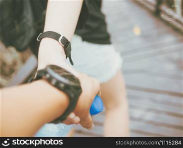 Couple in love holding hands while walking in outdoor park. man and girl wearing wrist watch. Close up.